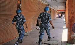 Jaipur: Rapid Action Force personnel walk past closed shops