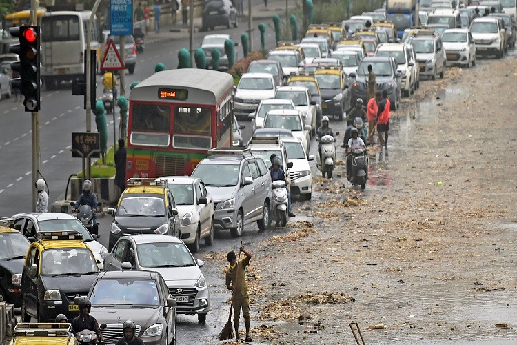 Brihanmumbai Municipal Corporation (BMC) workers clear the garbage washed ashore during high tide on a road along the Marine Drive in Mumbai on Friday.
