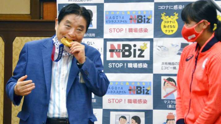 Nagoya Mayor Takashi Kawamura, left, bites the Olympic gold medal of Miu Goto